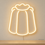 Watermarked concept mockup of Mini Canele LED Neon Sign in Warm White on a clear acrylic backboard.