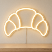 Watermarked concept mockup of Mini Croissant LED Neon Sign in Warm White on a clear acrylic backboard.