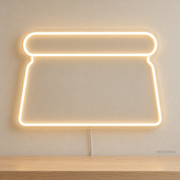 Watermarked concept mockup of Mini Dough Scraper LED Neon Sign in Warm White on a clear acrylic backboard.