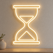 Watermarked concept mockup of Mini Hourglass LED Neon Sign in Warm White on a clear acrylic backboard.