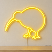 Watermarked concept mockup of Mini Kiwi Bird LED Neon Sign in Yellow on a clear acrylic backboard.