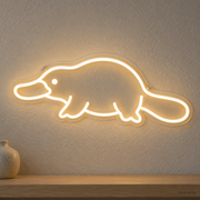Watermarked concept mockup of Mini Platypus LED Neon Sign in Warm White on a clear acrylic backboard.